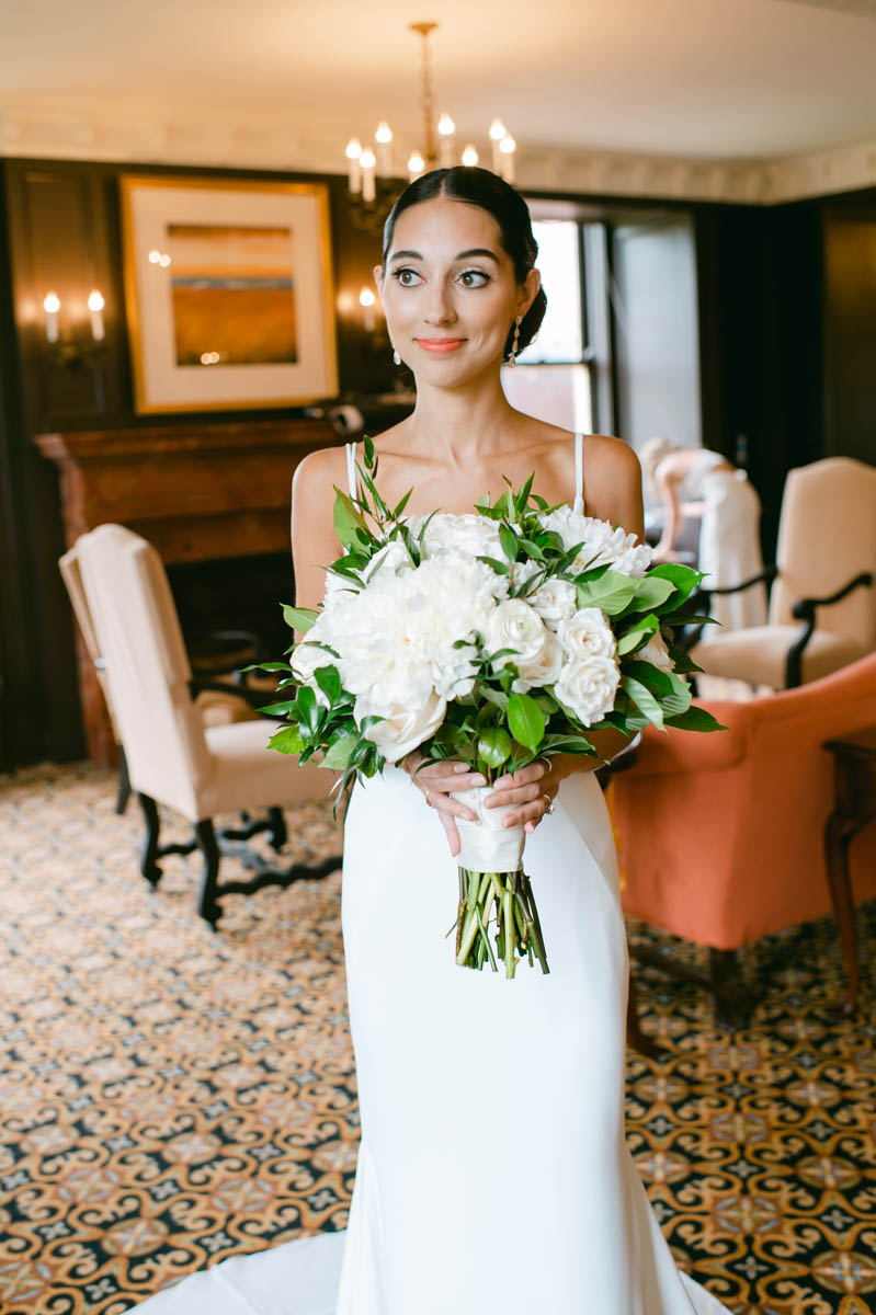 Bride poses with white wedding bouquet