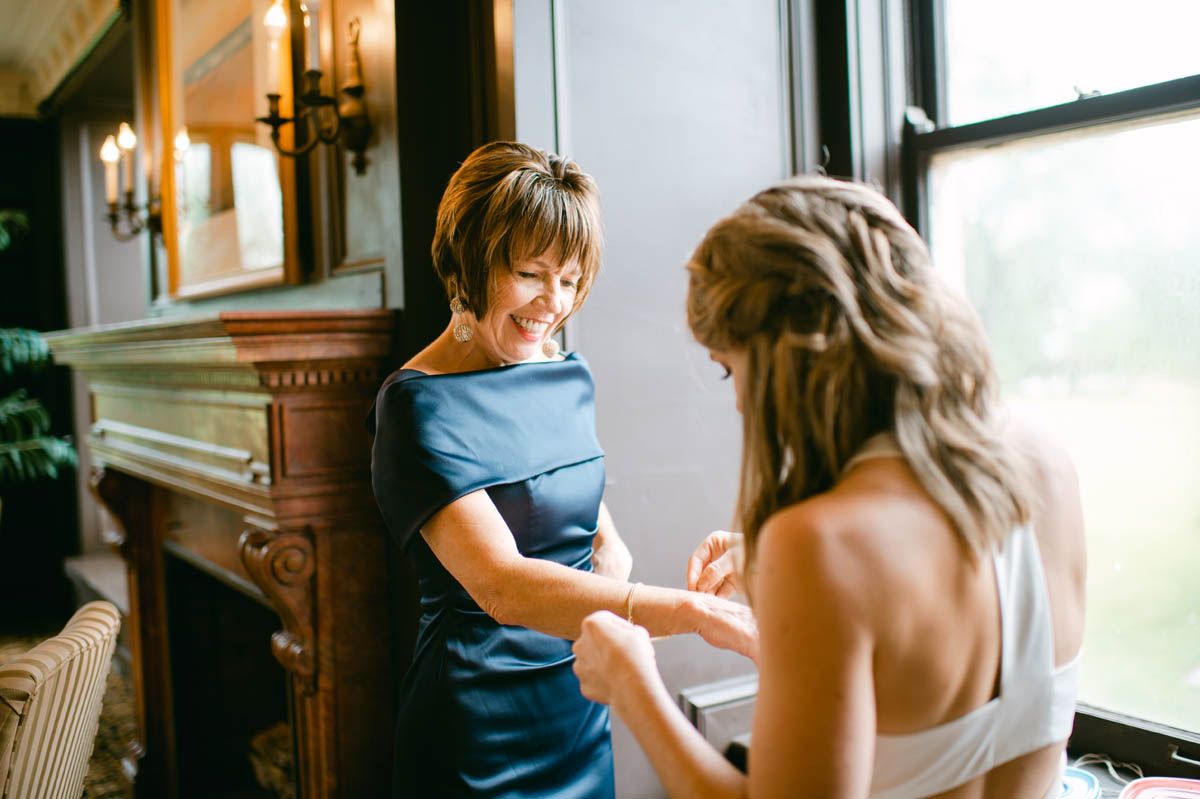 Bride's mom putting on bracelet.