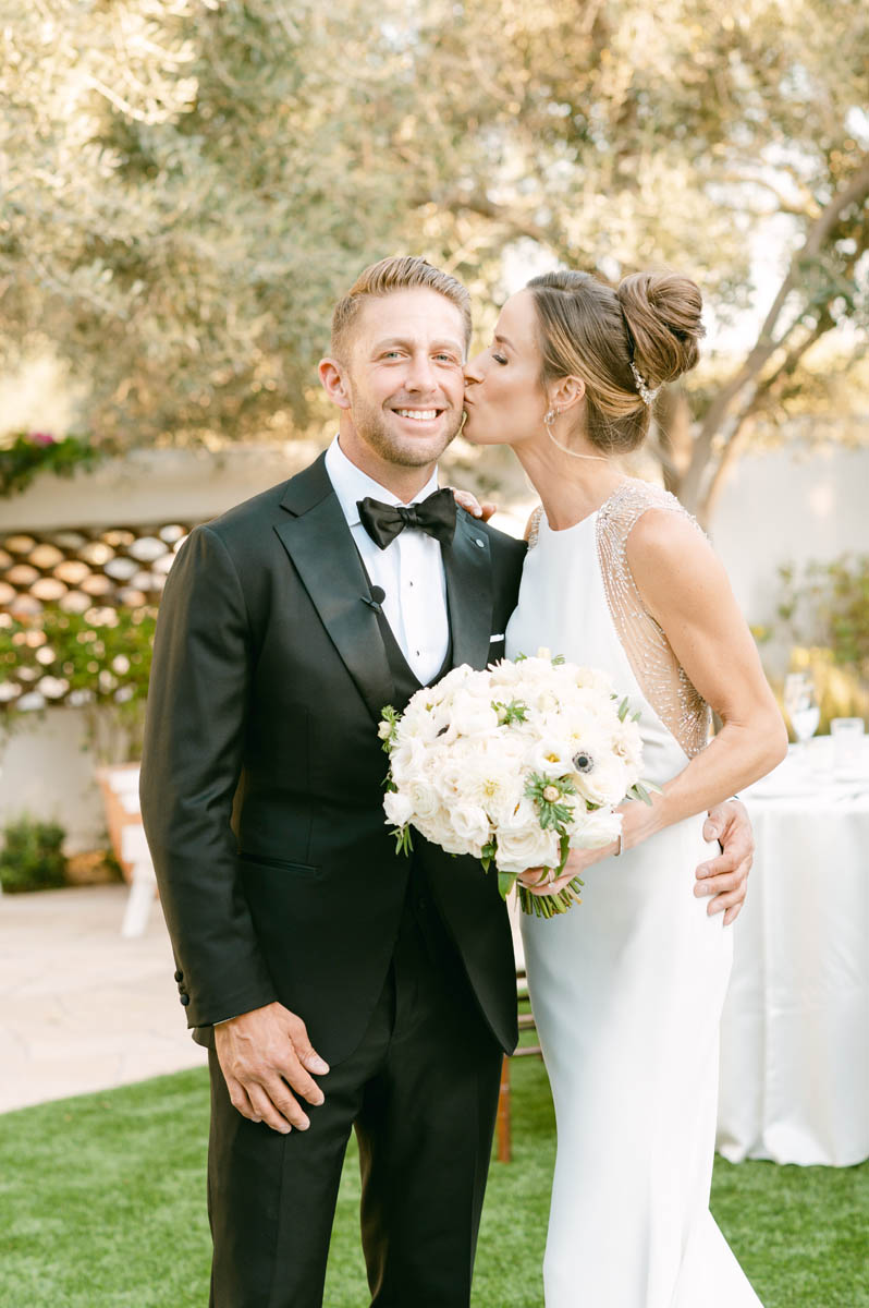 Beautiful bride kisses groom on the cheek.