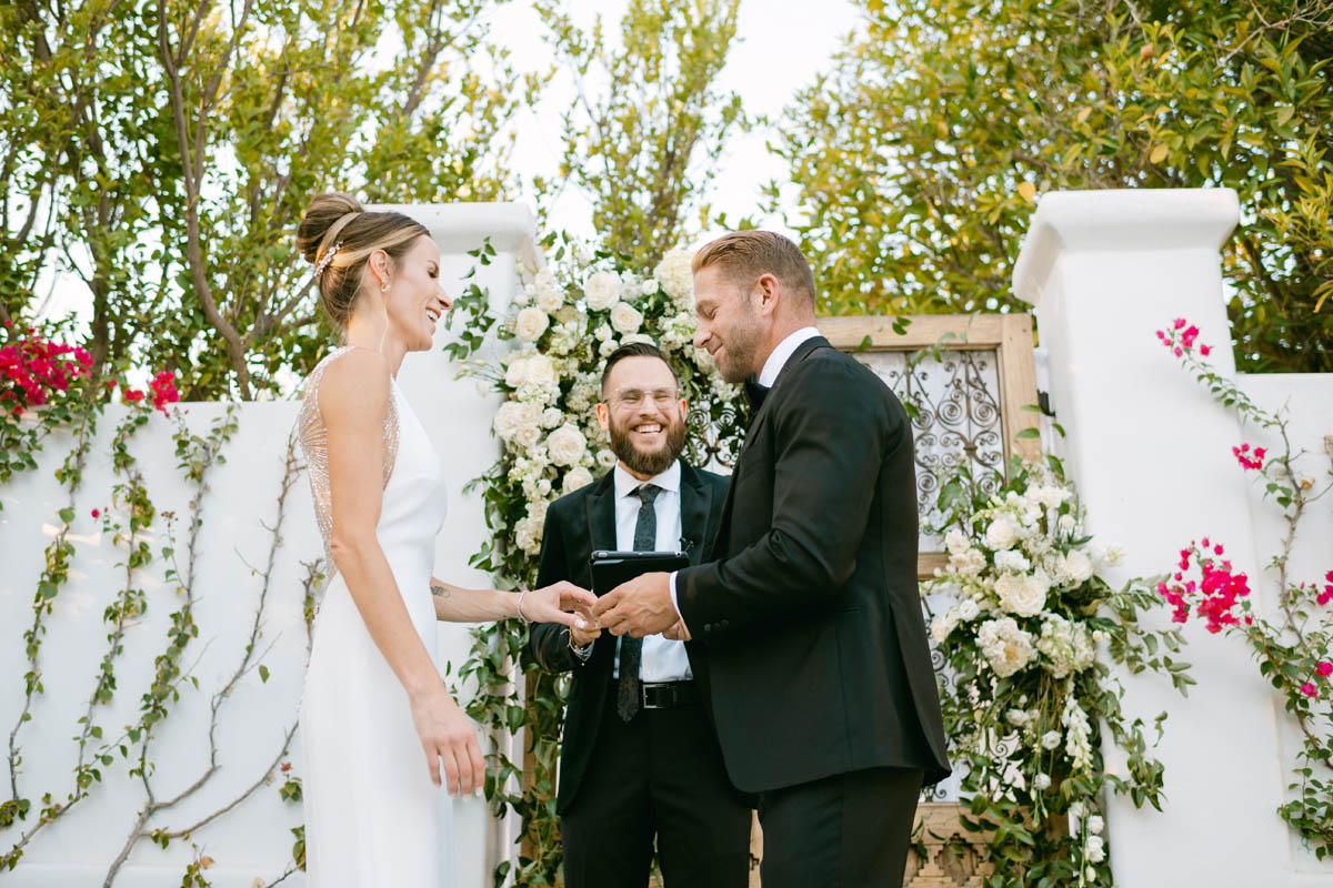 Groom puts ring on bride's finger at wedding ceremony.