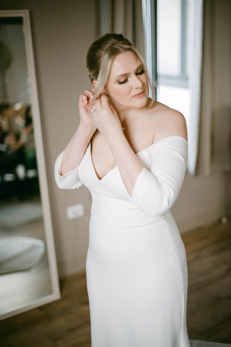 Beautiful bride putting on earrings at Walden Chicago.