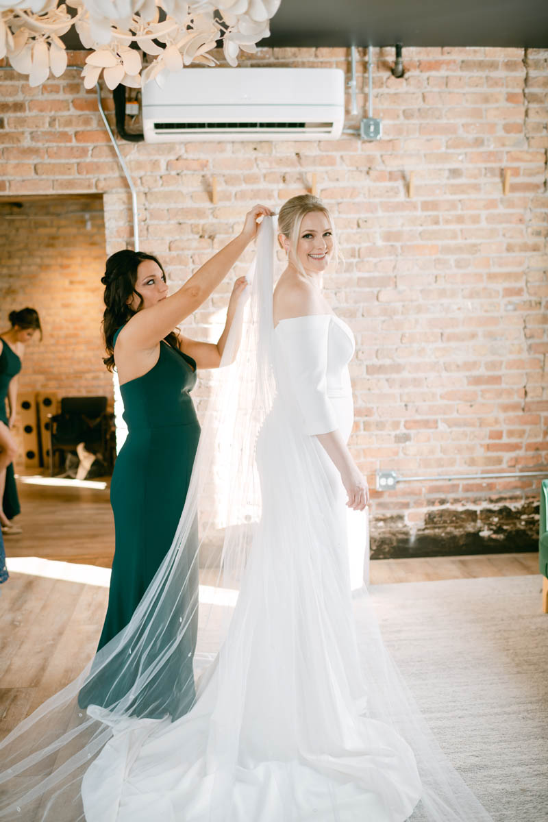 Bridesmaid putting on bride's veil at Walden.
