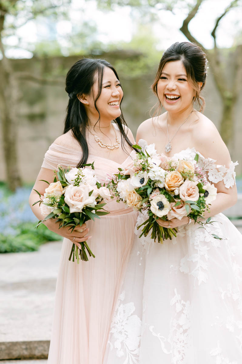 Bride and bridesmaid laugh together.