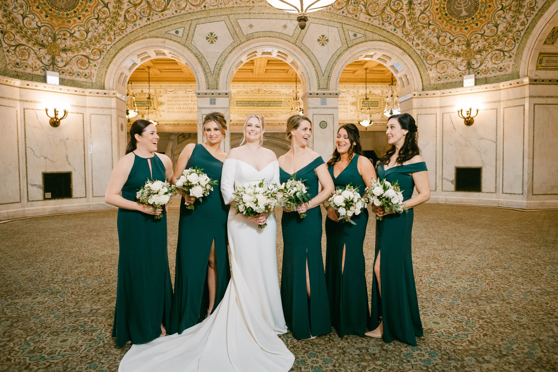 Bridesmaids in green dresses taking wedding photos.