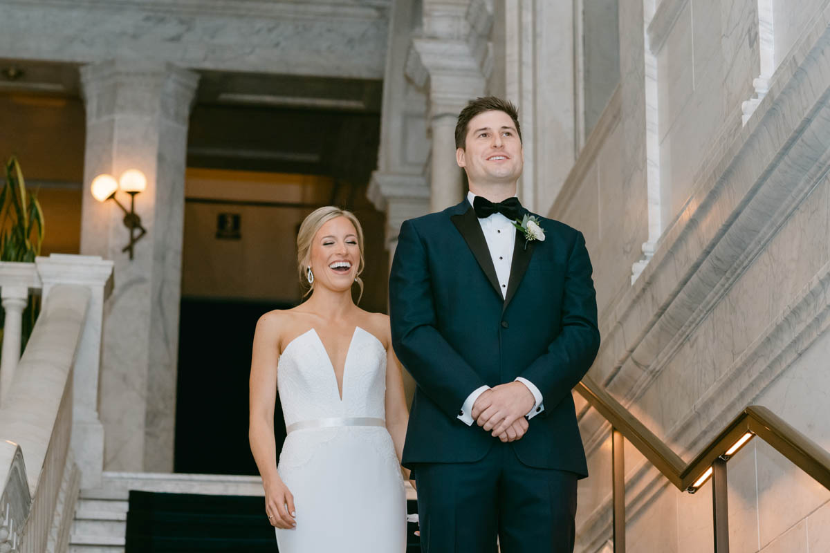 Bride laughs behind her groom.