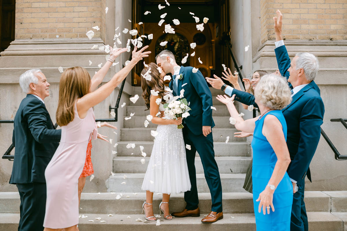 Guests throwing rose petals at bride and groom.