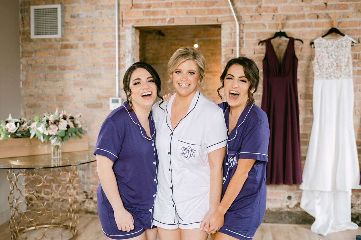 Bride laughing with bridesmaids in purple pajamas.