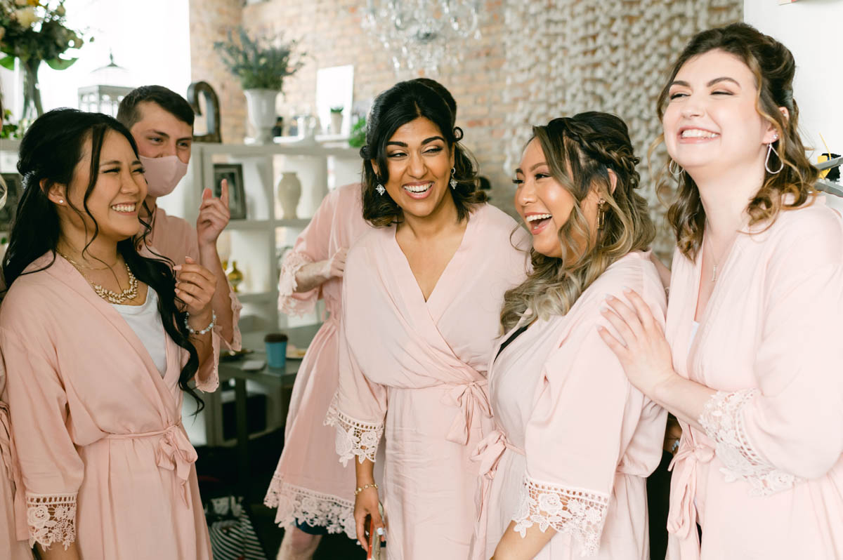 Bridesmaids in pink pajamas laughing.
