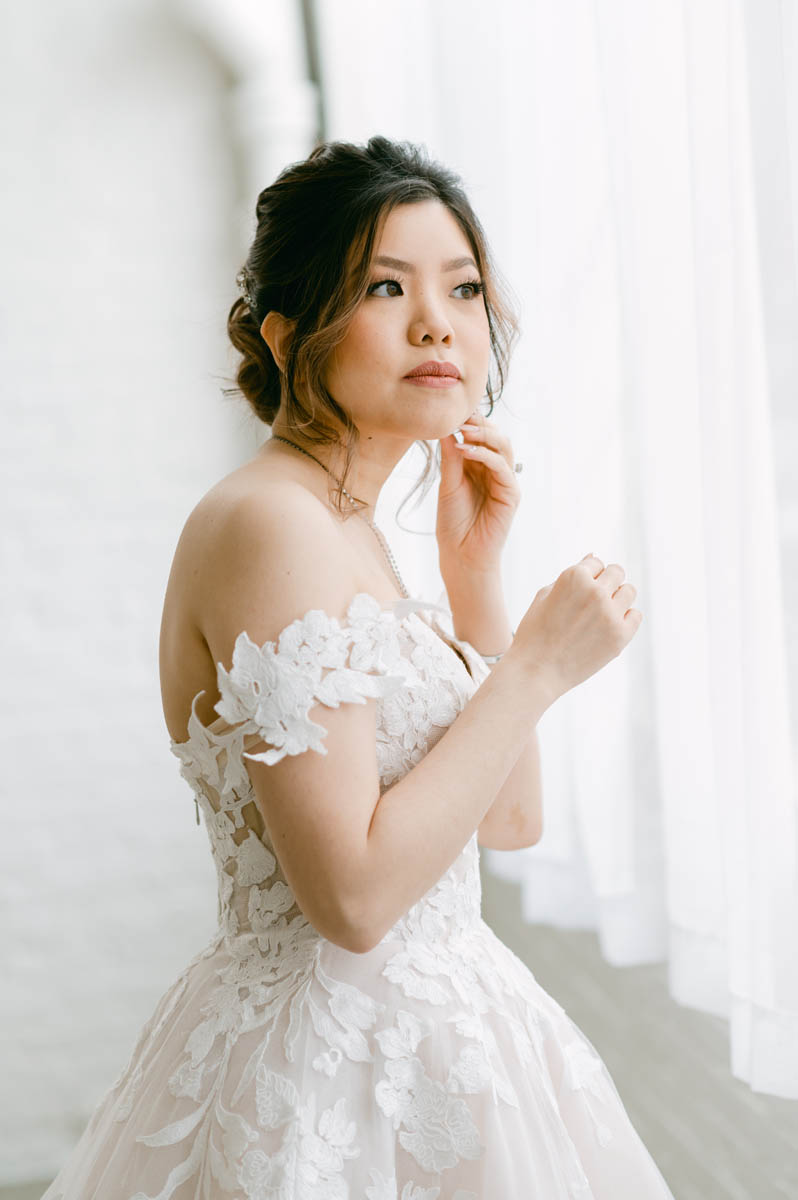 Beautiful bride putting on earrings.