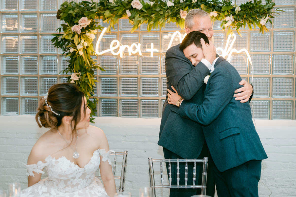 Groom hugs his dad at wedding reception.
