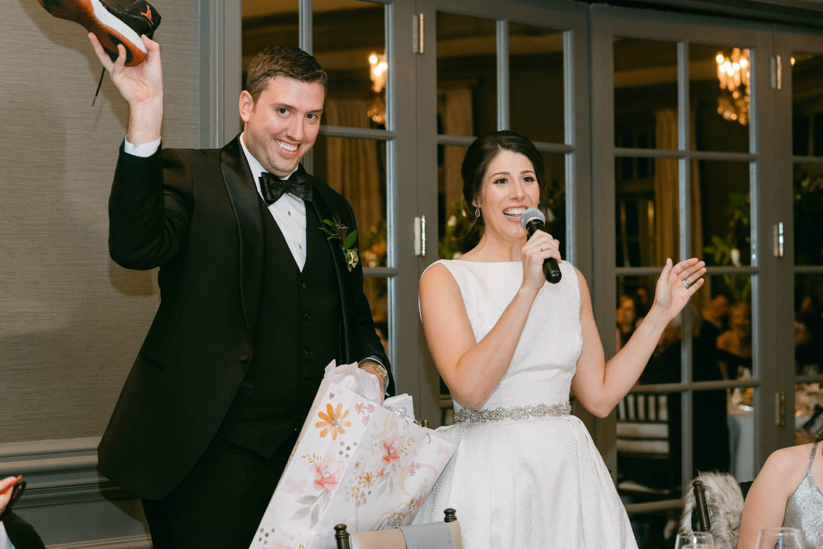 Groom opening sneakers wedding gift at reception.