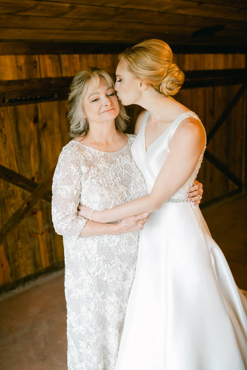 Bride kissing her mom on her wedding day.