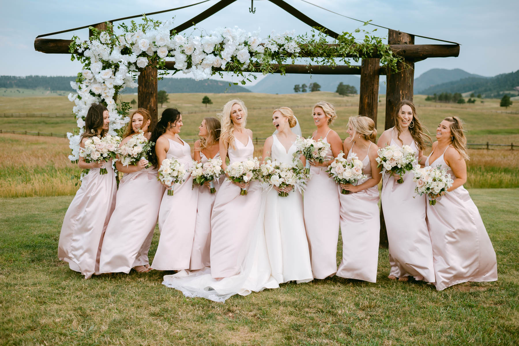 Bridesmaids in pink dresses post for wedding photos at Spruce Mountain Ranch.