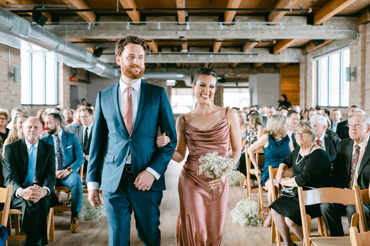 Bridesmaids in blush dress walking down the aisle.