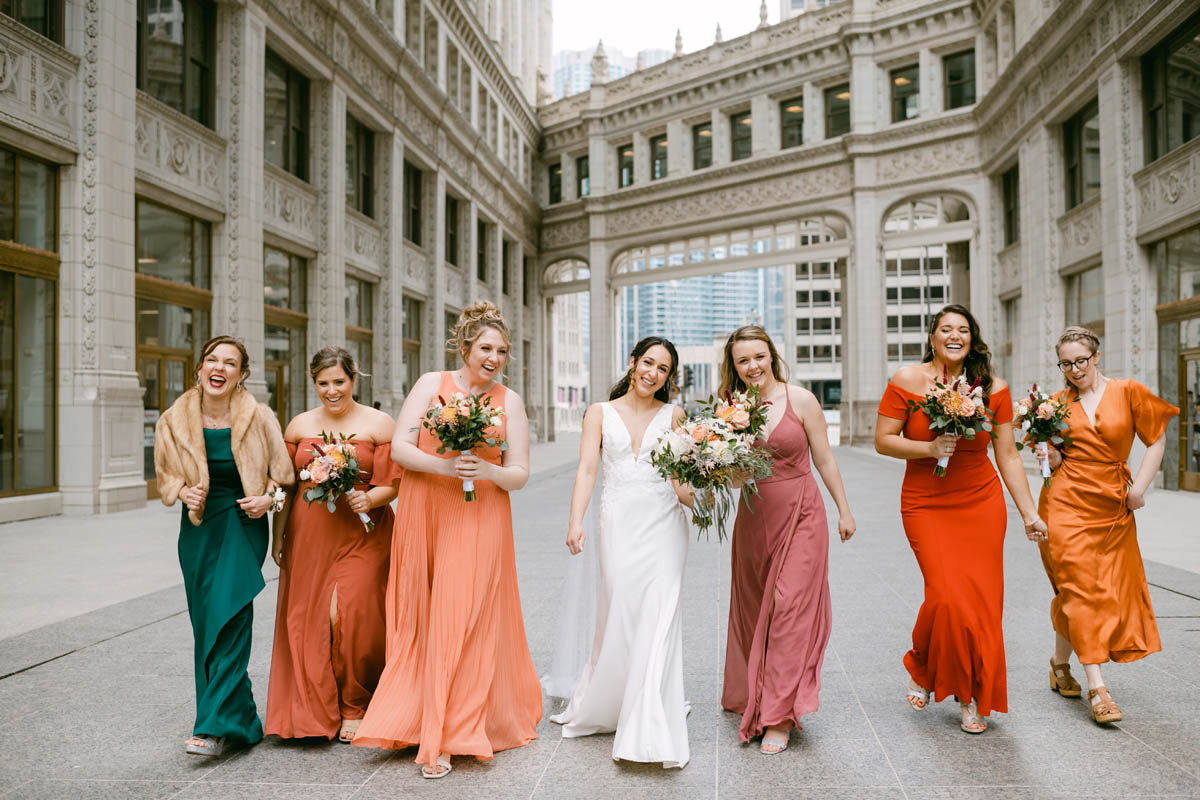 Bridesmaids in blush dresses pose for wedding photos at the Wrigley Building.
