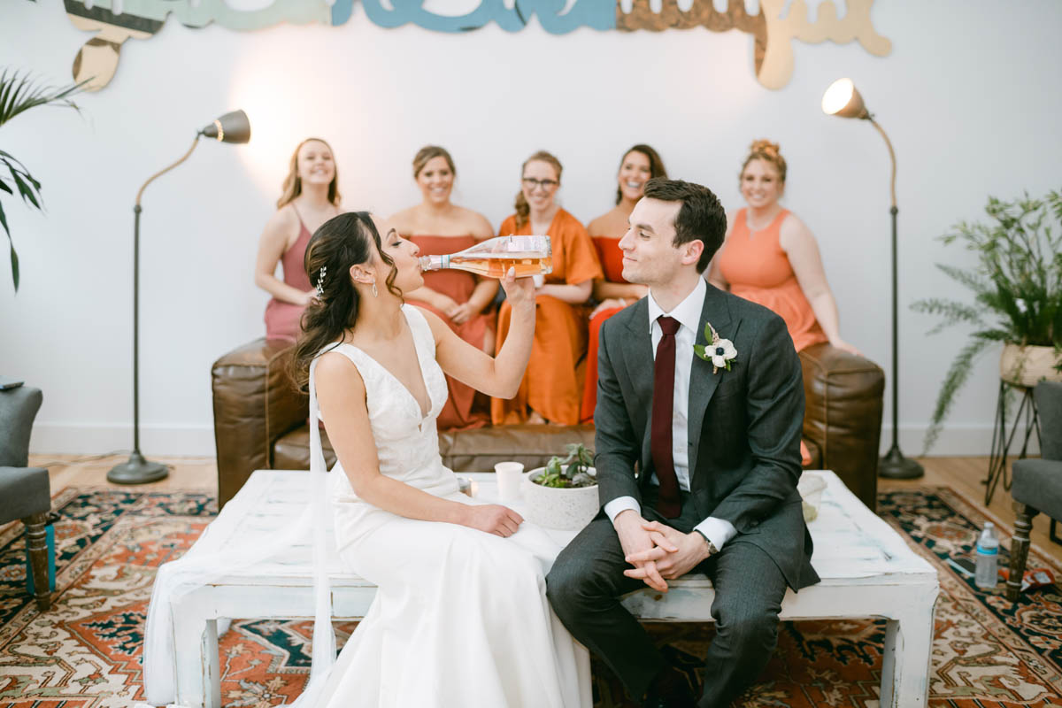 Greenhouse Loft wedding bride drinking wine.
