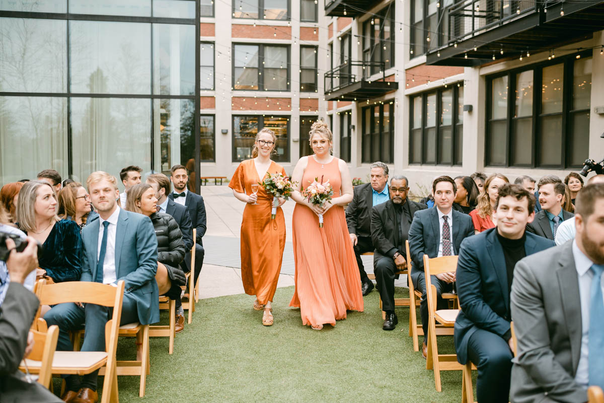 Bridesmaids in orange dresses at Greenhouse Loft wedding.