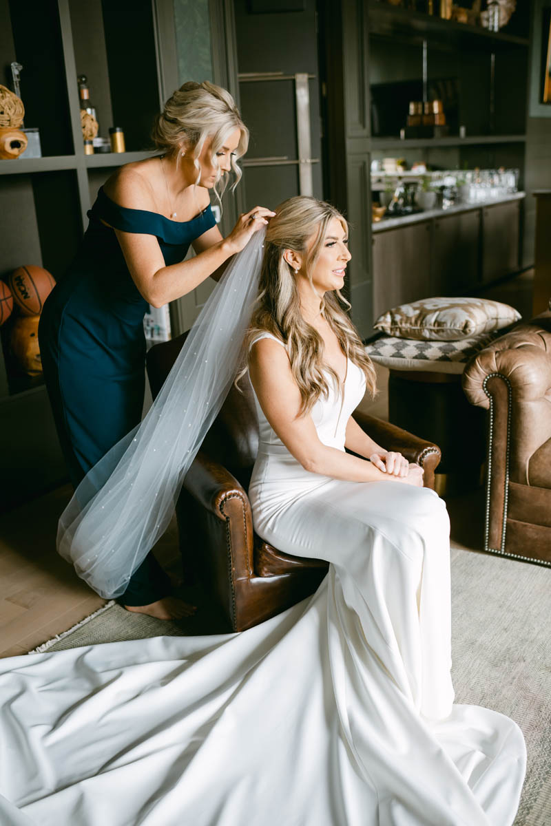 Maid of honor putting cathedral veil on bride.