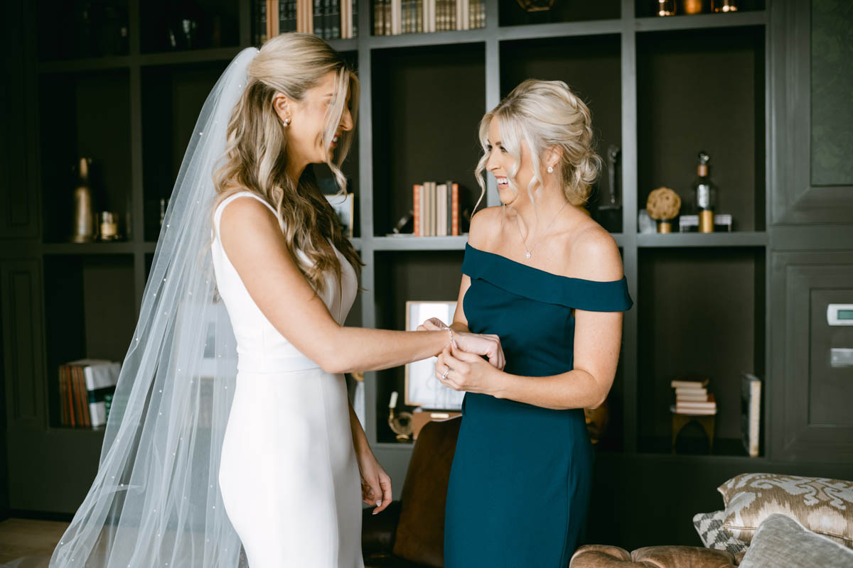 Bridesmaid putting bracelet on bride