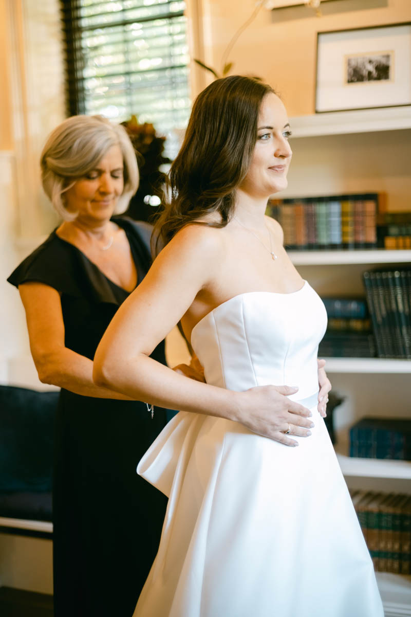 Mom helping bride get into wedding dress