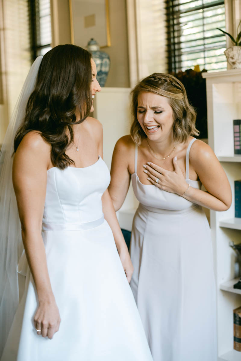 Bridesmaid laughing with bride