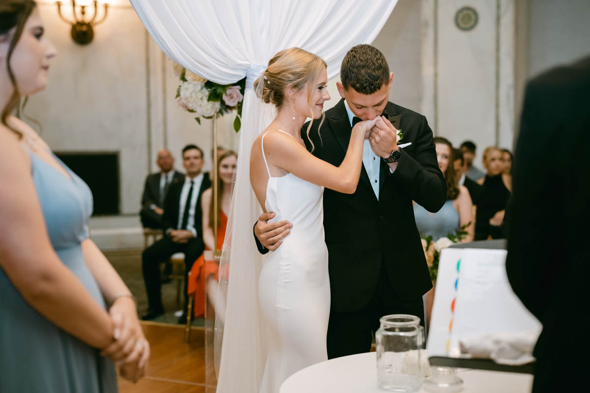 groom kissing his brides hand at chicago cultural center wedding