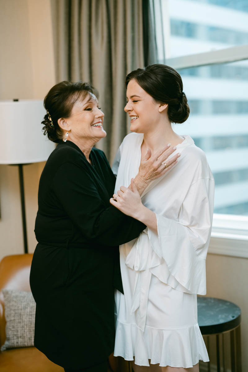 bride and mom laughing on wedding day