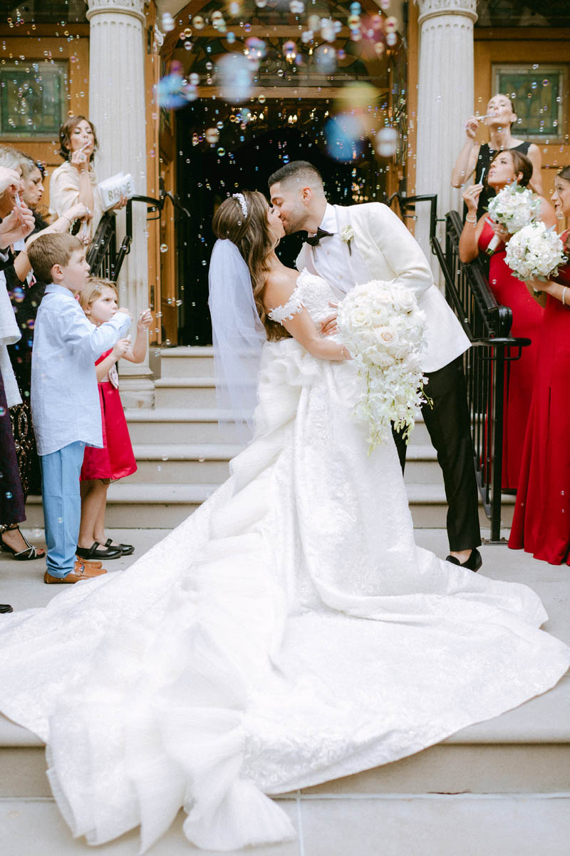 Bride and groom kiss surrounded by bubbles