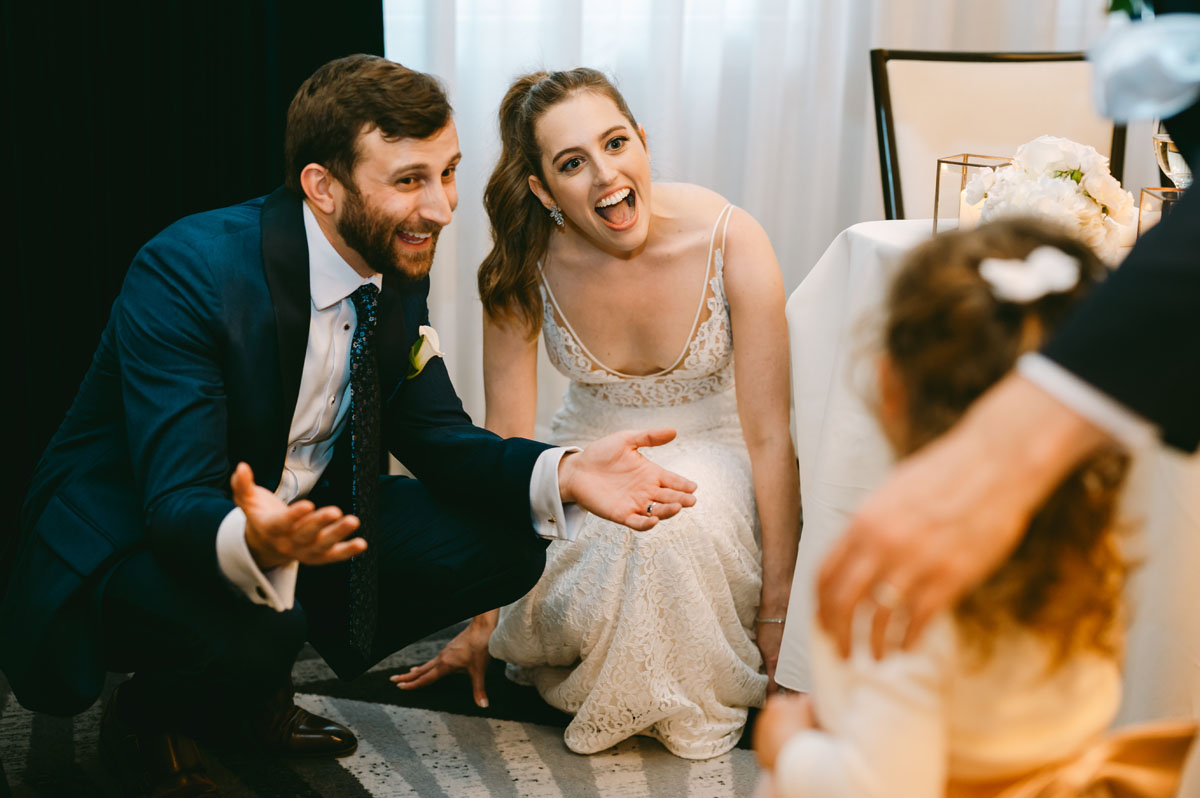 bride and groom playing with flower girl