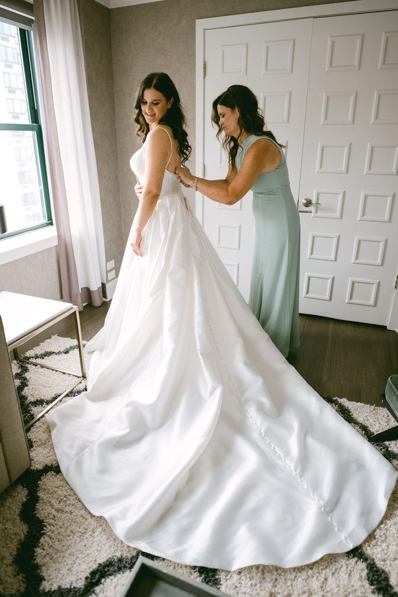 mom helping bride into wedding dress at Claridge House