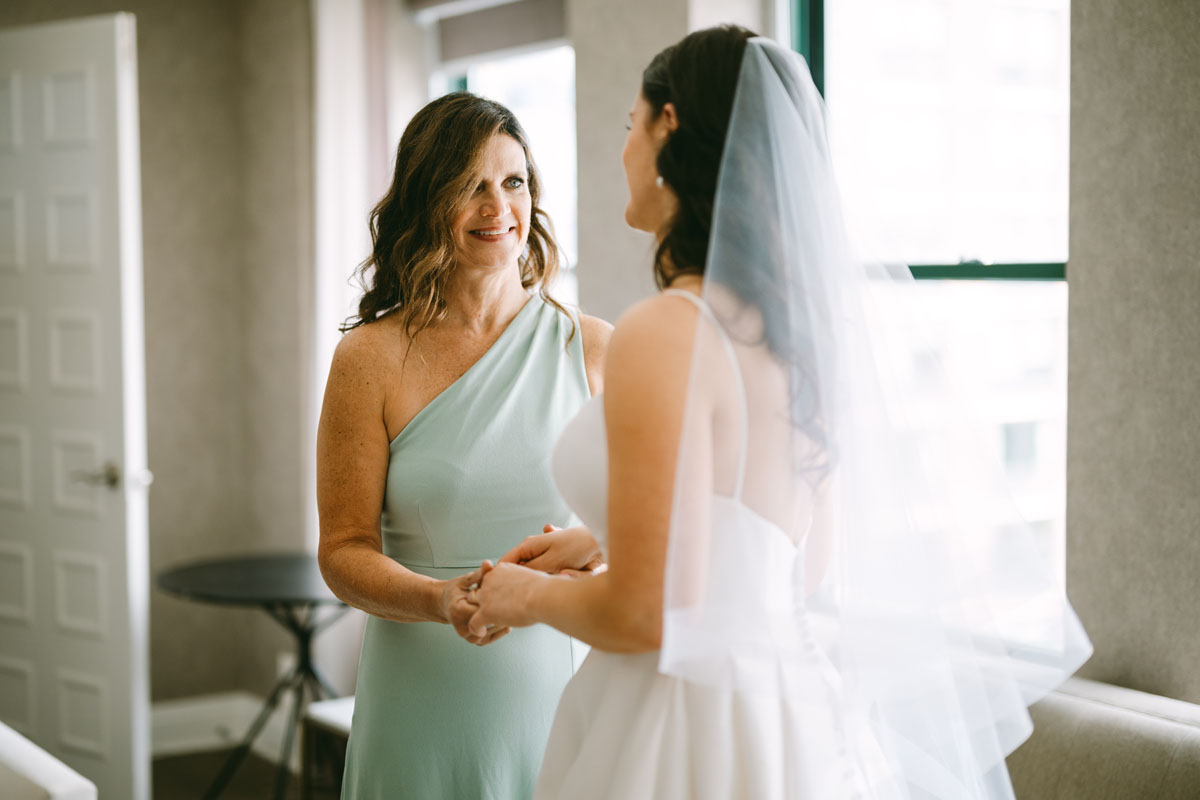 mom helping bride get ready on wedding day