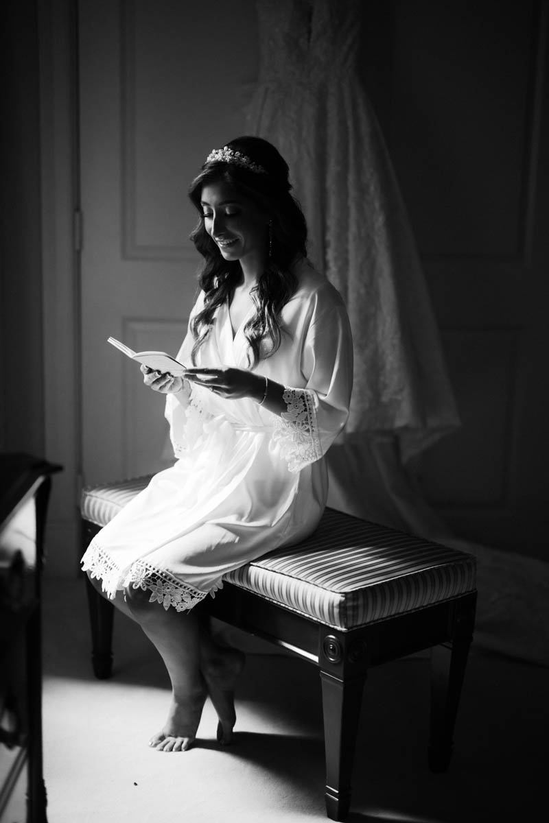 Black and white photo of bride reading a card from the groom before ceremony
