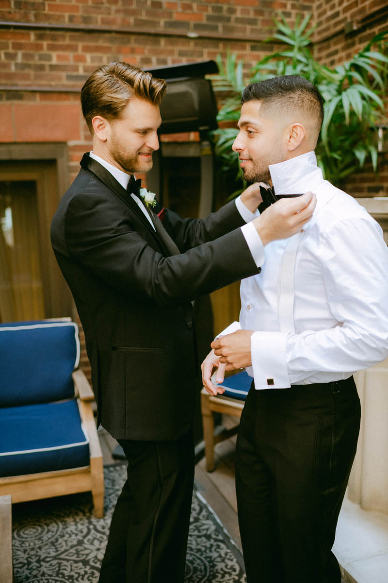 Groom adjusting his tie with help from best man