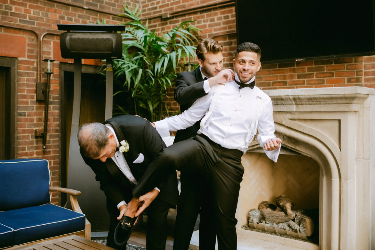 Groom adjusting his suit with help from his dad