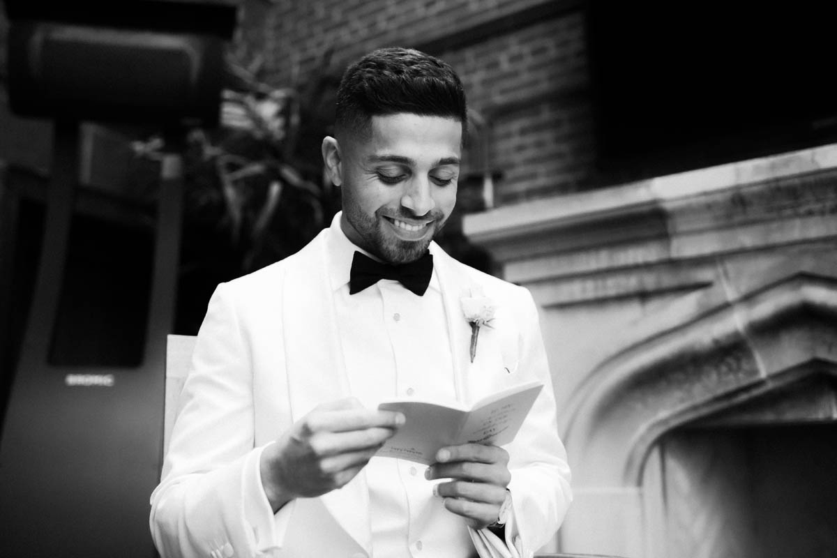 Black and white portrait of groom reading card from his bride