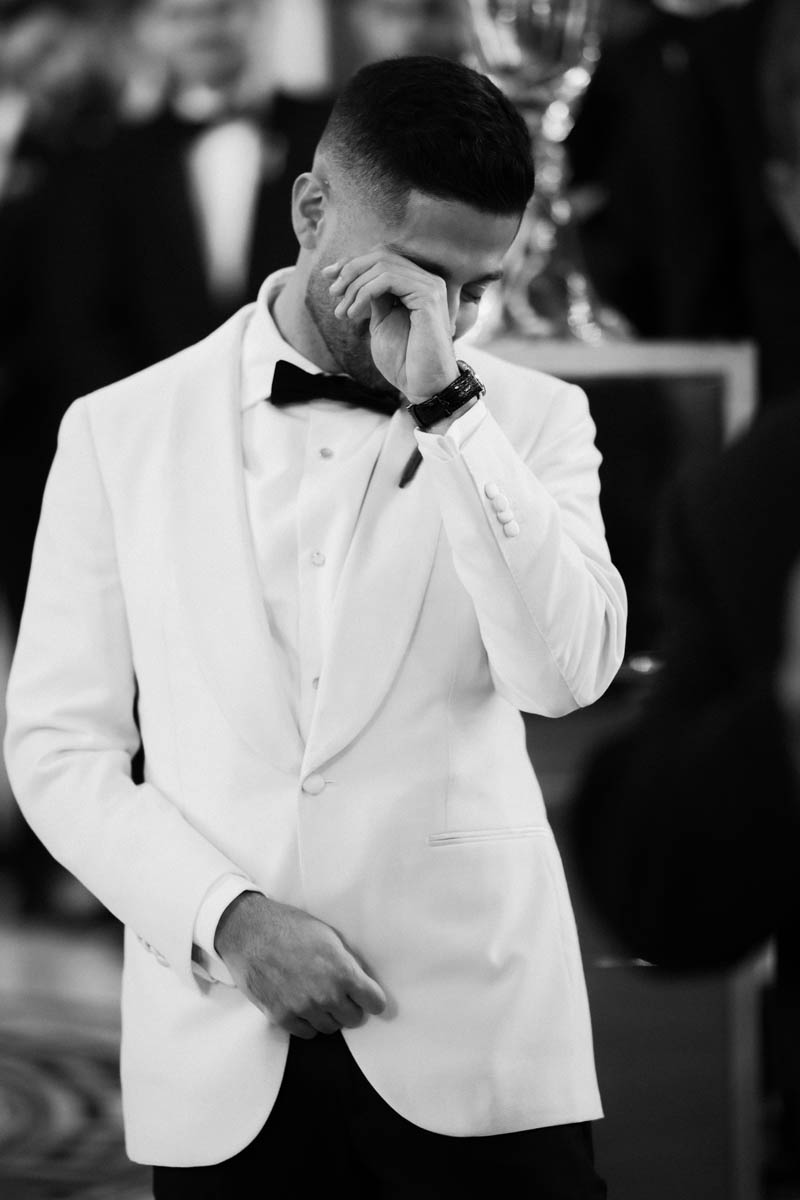 Black and white photo of groom wiping tears