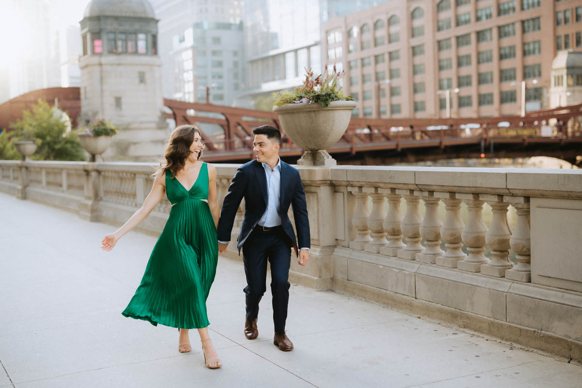 Chicago engagement photo of a couple walking together along a downtown stone railing