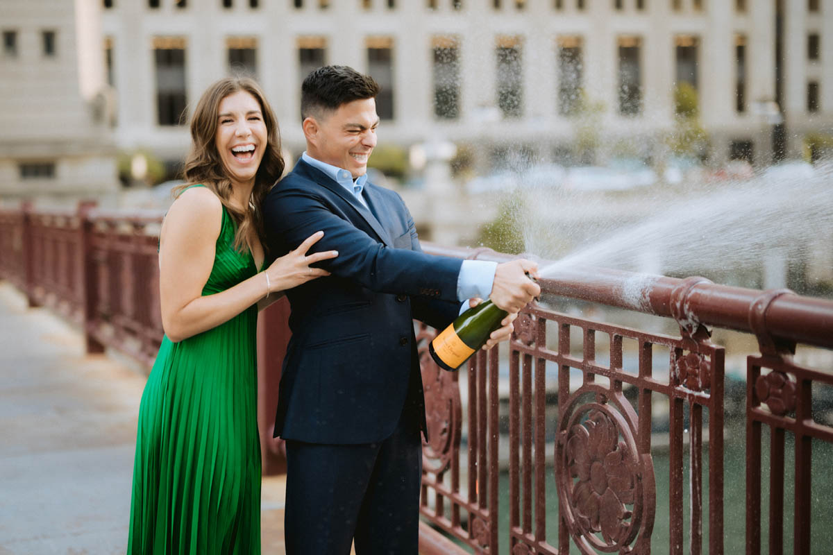 Chicago engagement photos of a couple laughing together with champagne