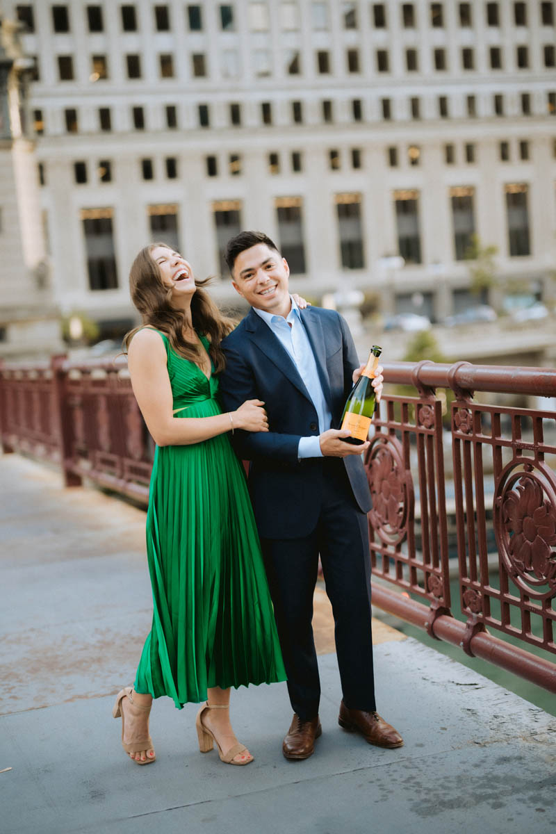 Chicago engagement photos of a couple laughing together with champagne