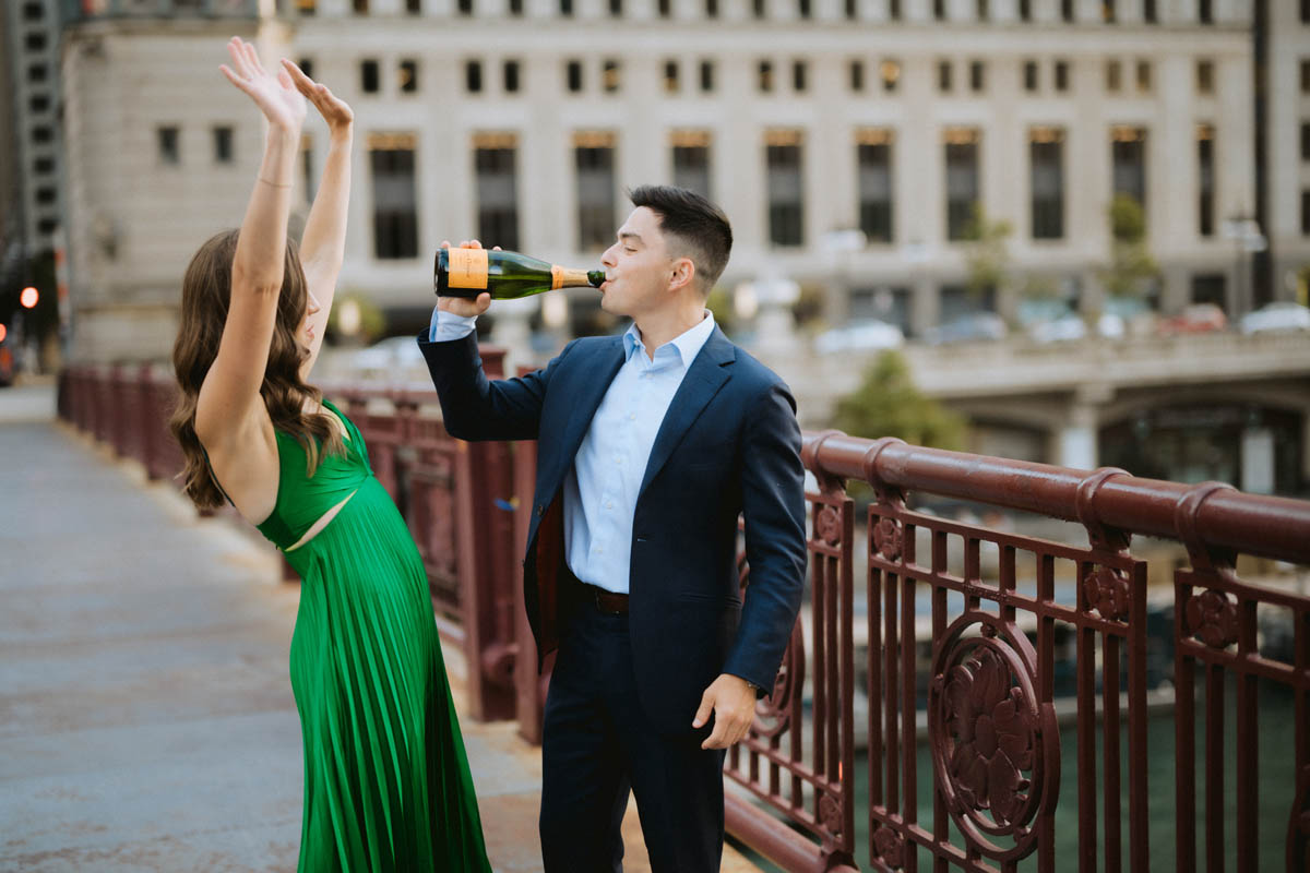 Chicago engagement photo of a couple celebrating with champagne on a city bridge