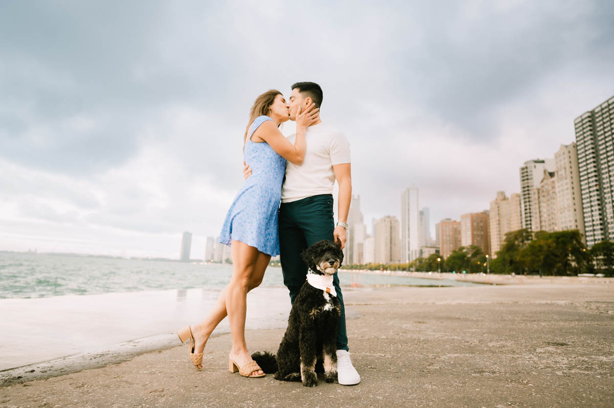 Chicago engagement photo of a couple walking with their dog along the Lake Michigan shoreline