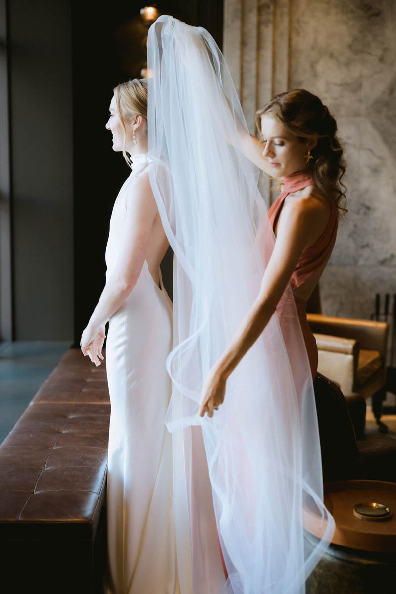 Bride and bridesmaid putting on veil