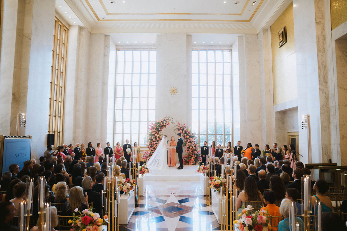 Bride and groom standing beneath a floral wedding ceremony arch