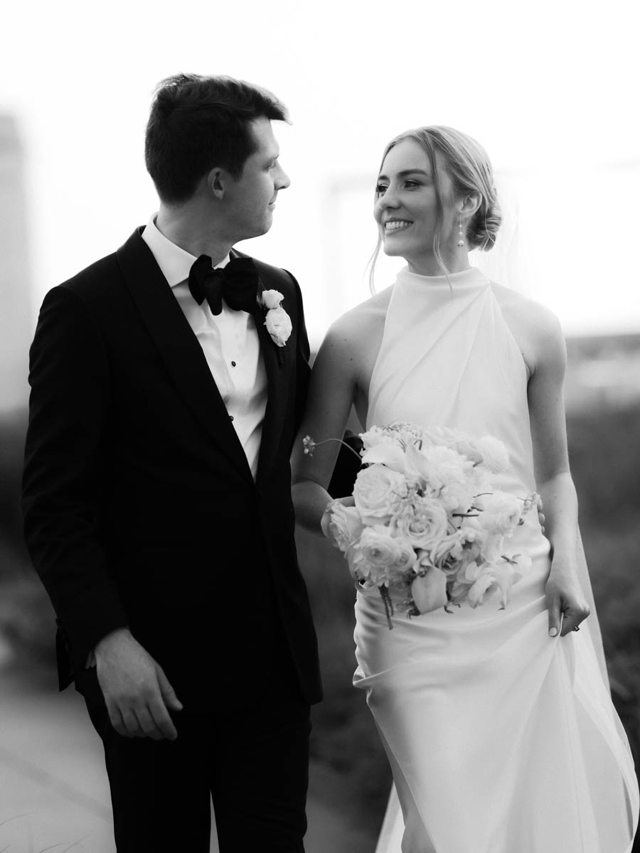 Black and white portrait of bride and groom walking together on the rooftop of the Old Post Office