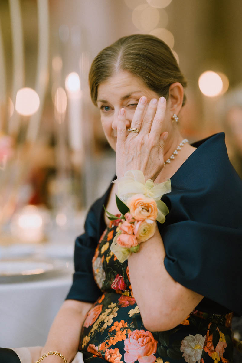 Groom's mom is wiping away tears during wedding toast.