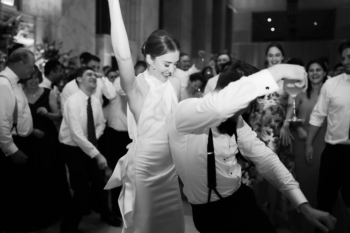 Black and white photo of bride and wedding guests dancing
