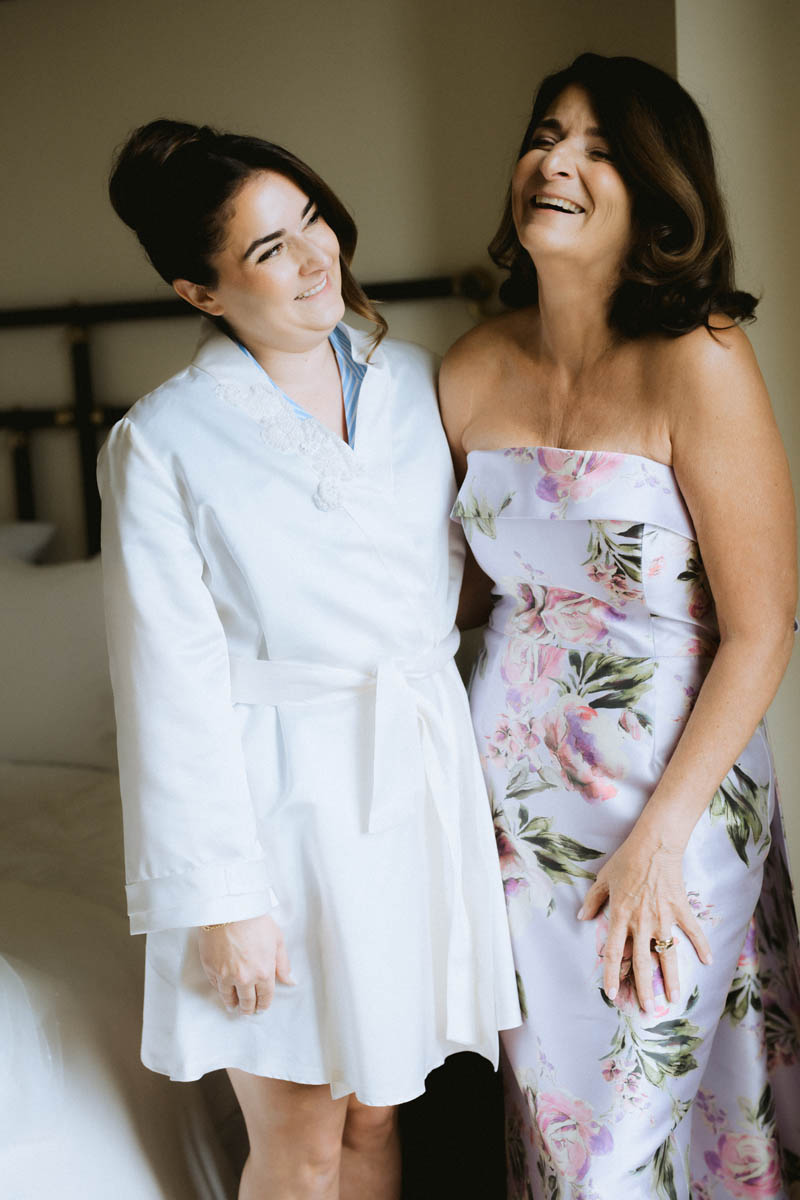 Bride and mom laughing while wearing a robe made of her mom's wedding dress