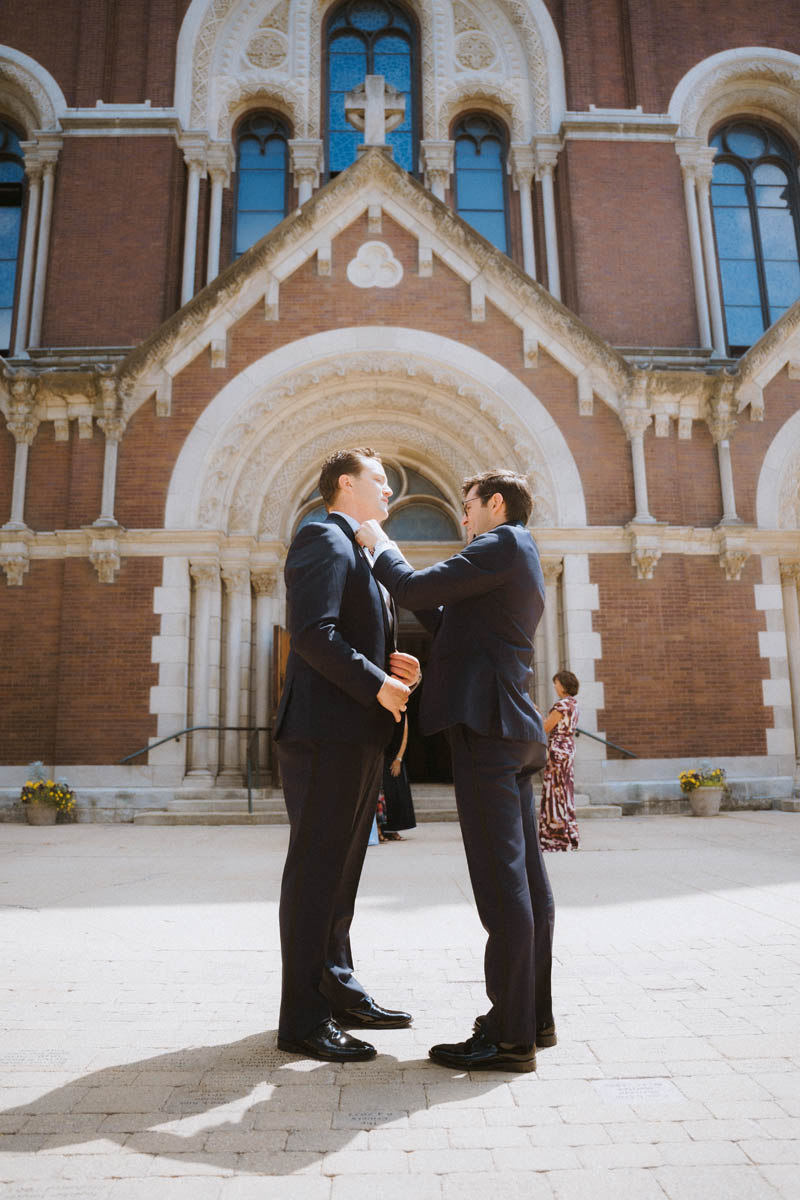 Groomsmen fixing their ties in front of the church