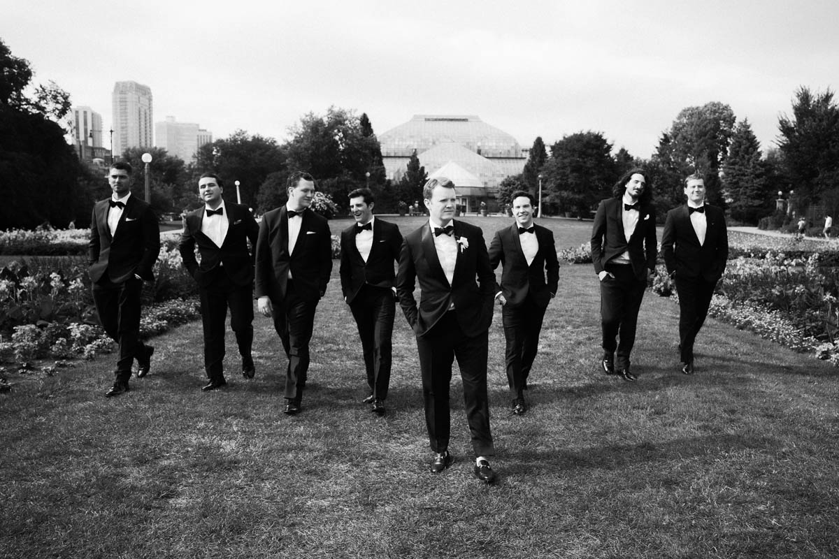 Black and white portrait of groom walking with groomsmen