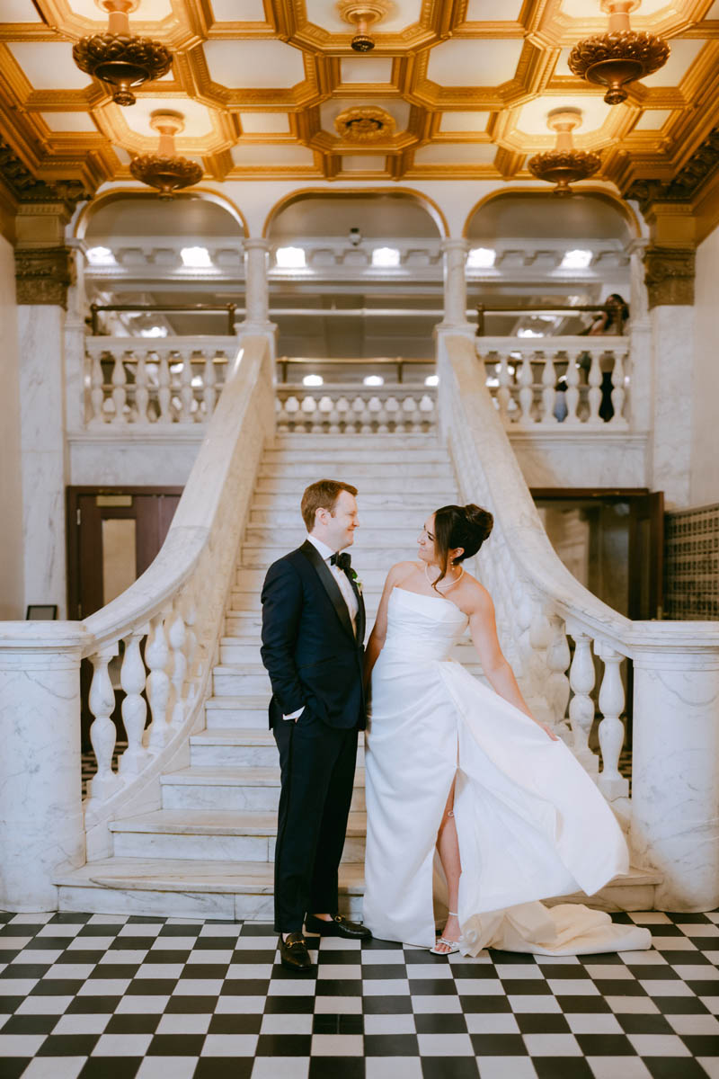 Bride and groom posing for photos in front of the grand staircase